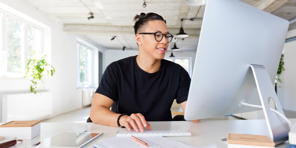 A younger man with glasses working at his computer