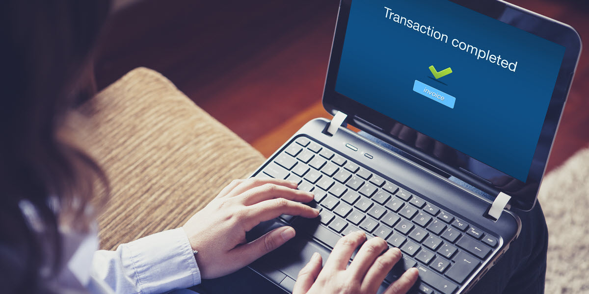 Hands on keyboard. Computer screen reads "transaction completed"