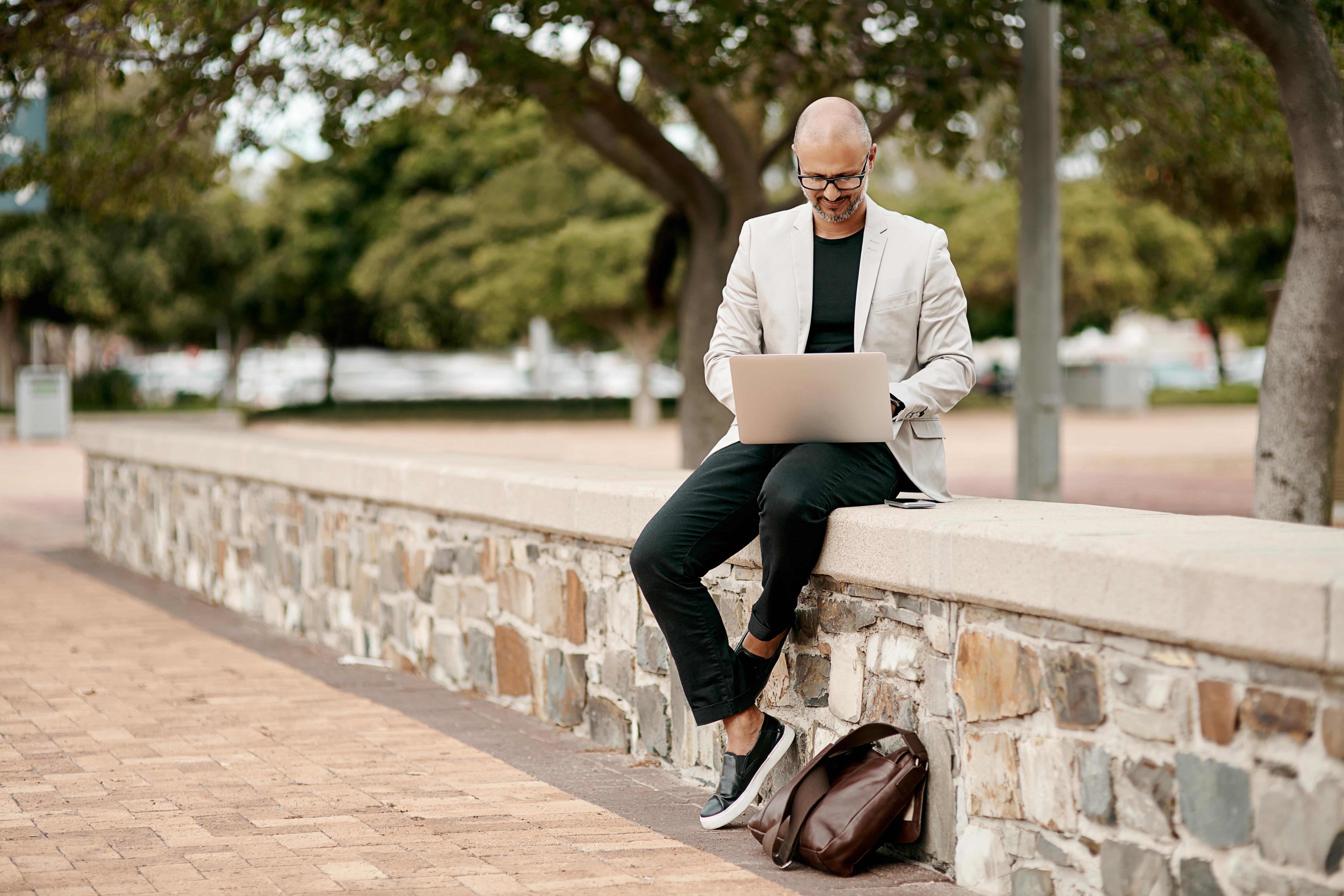 Man sitting on wall on computer