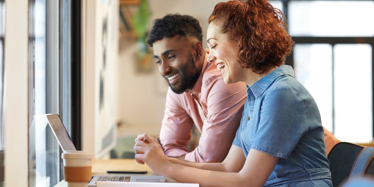 Two co-workers looking over a laptop
