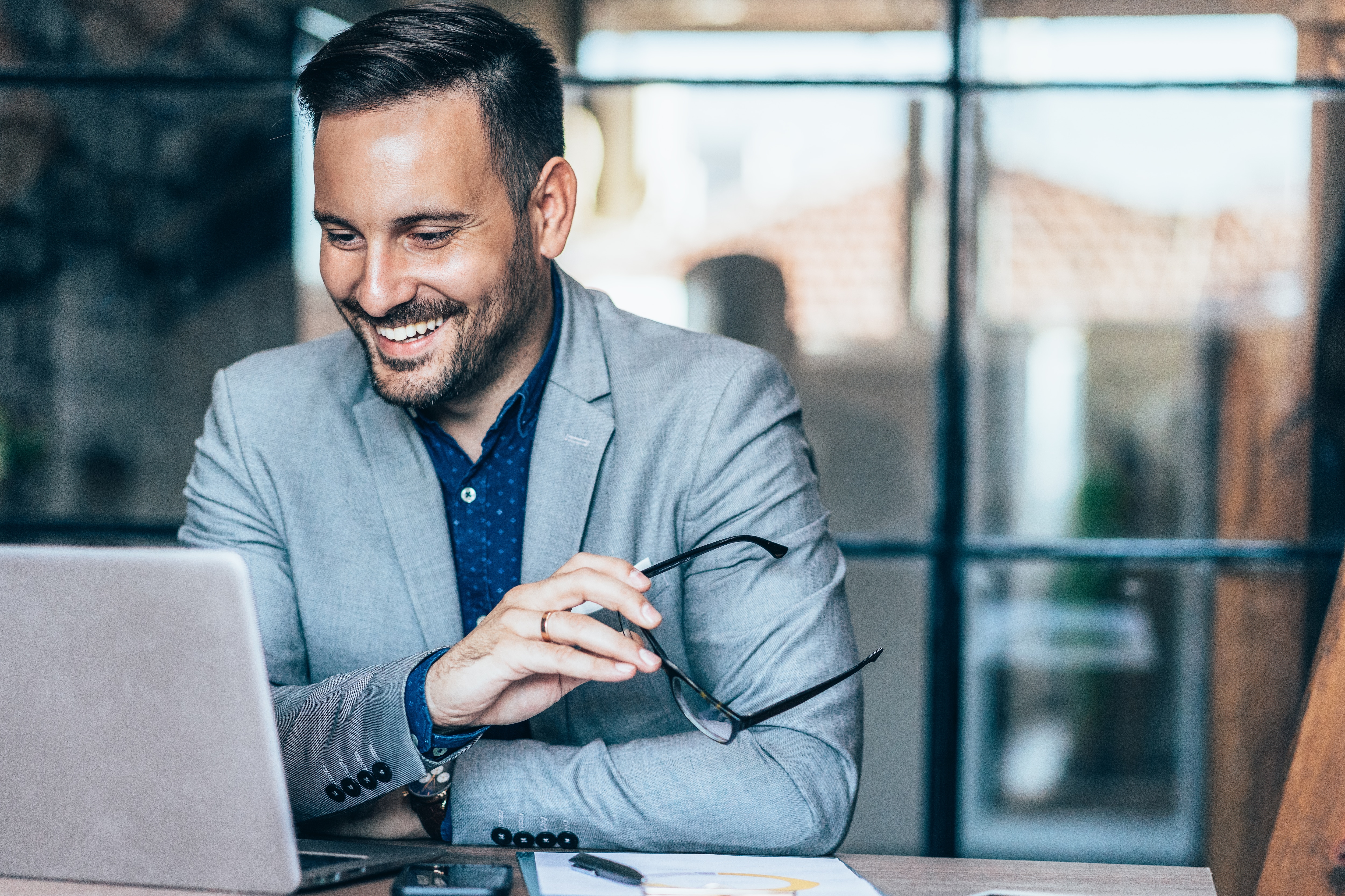 Man in suit sitting smiling looking at his laptop