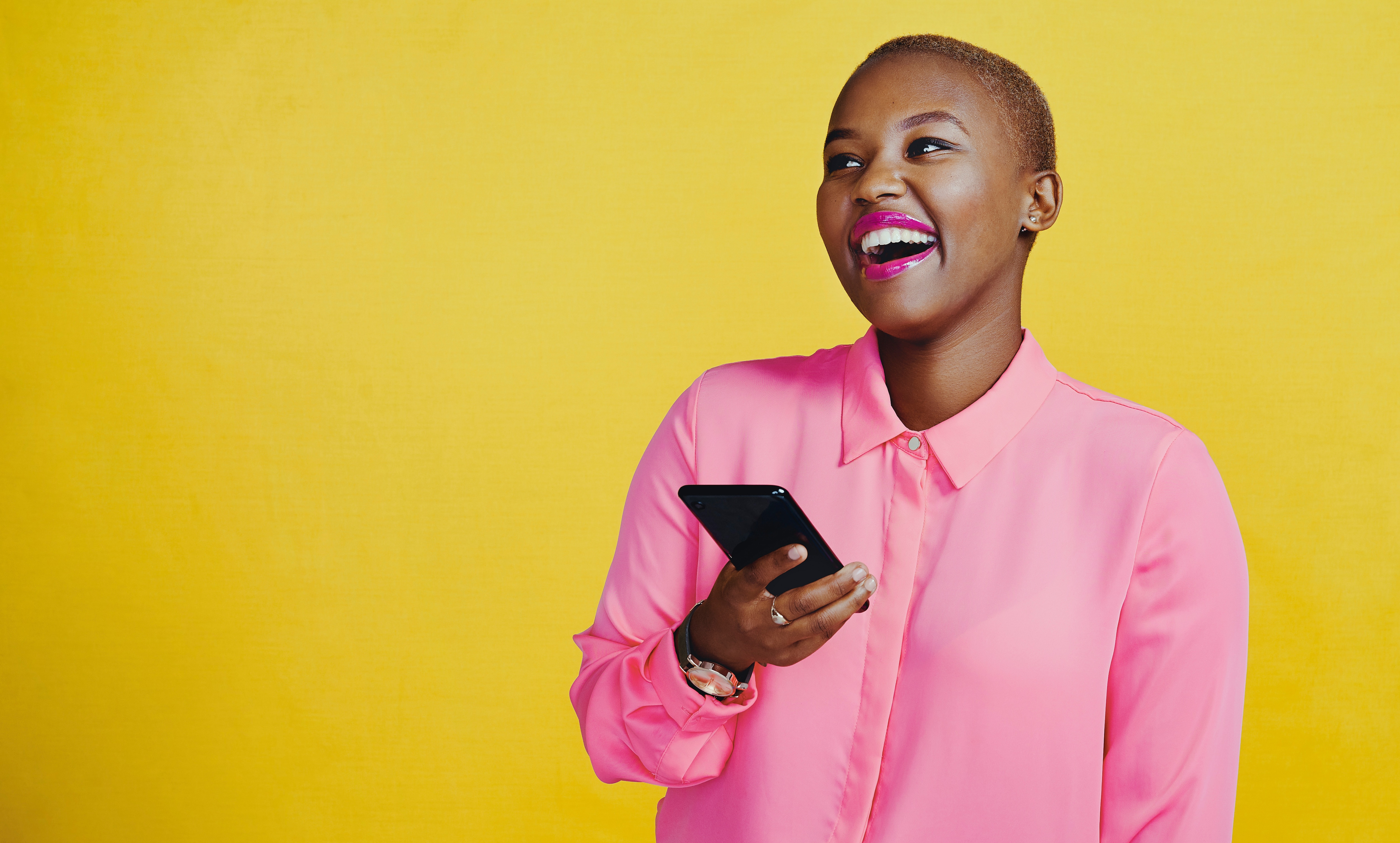 Woman on phone smiling with a yellow background