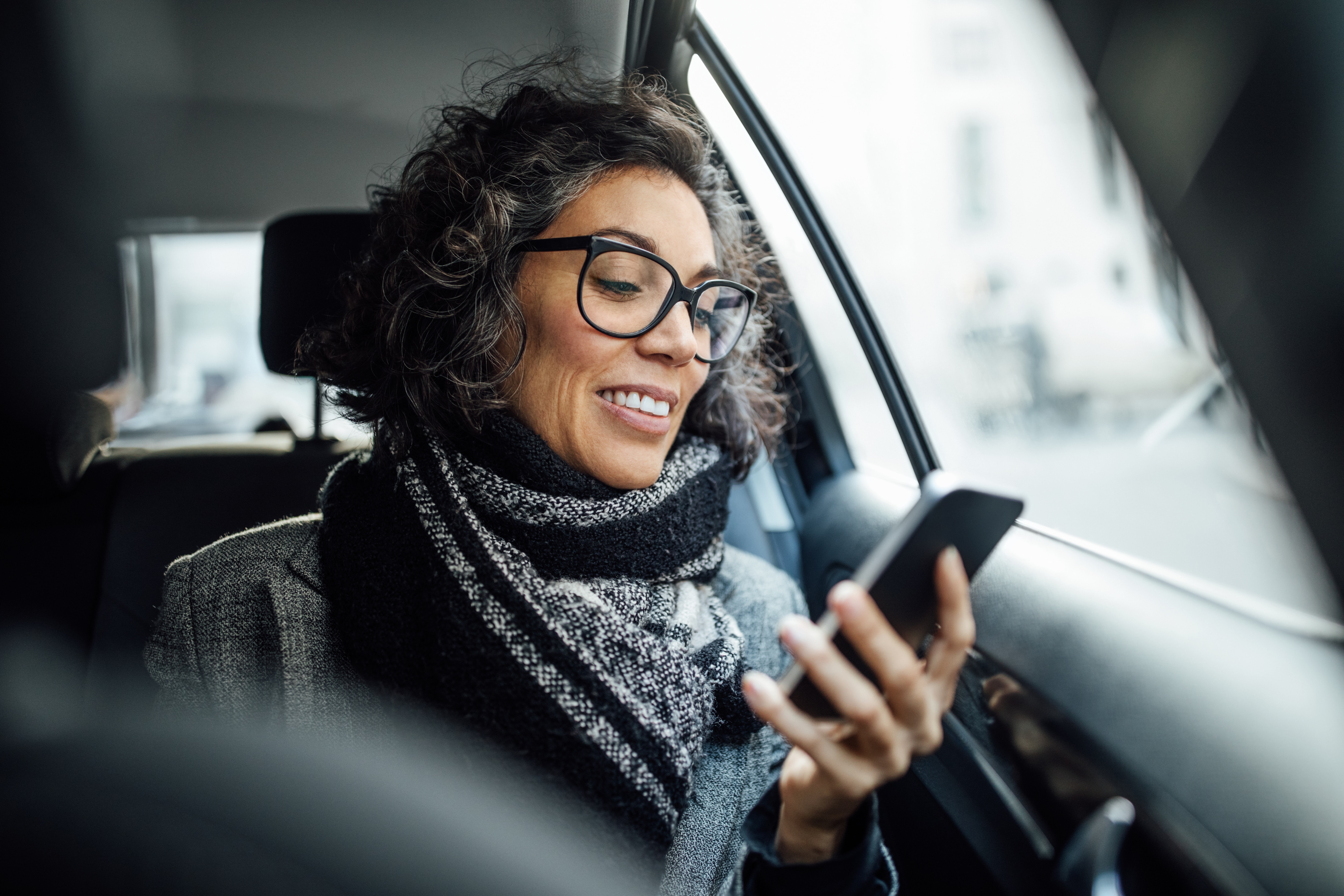 Businesswoman checks her phone in a car