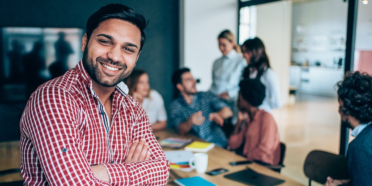Smiling man in front of group meeting at a table