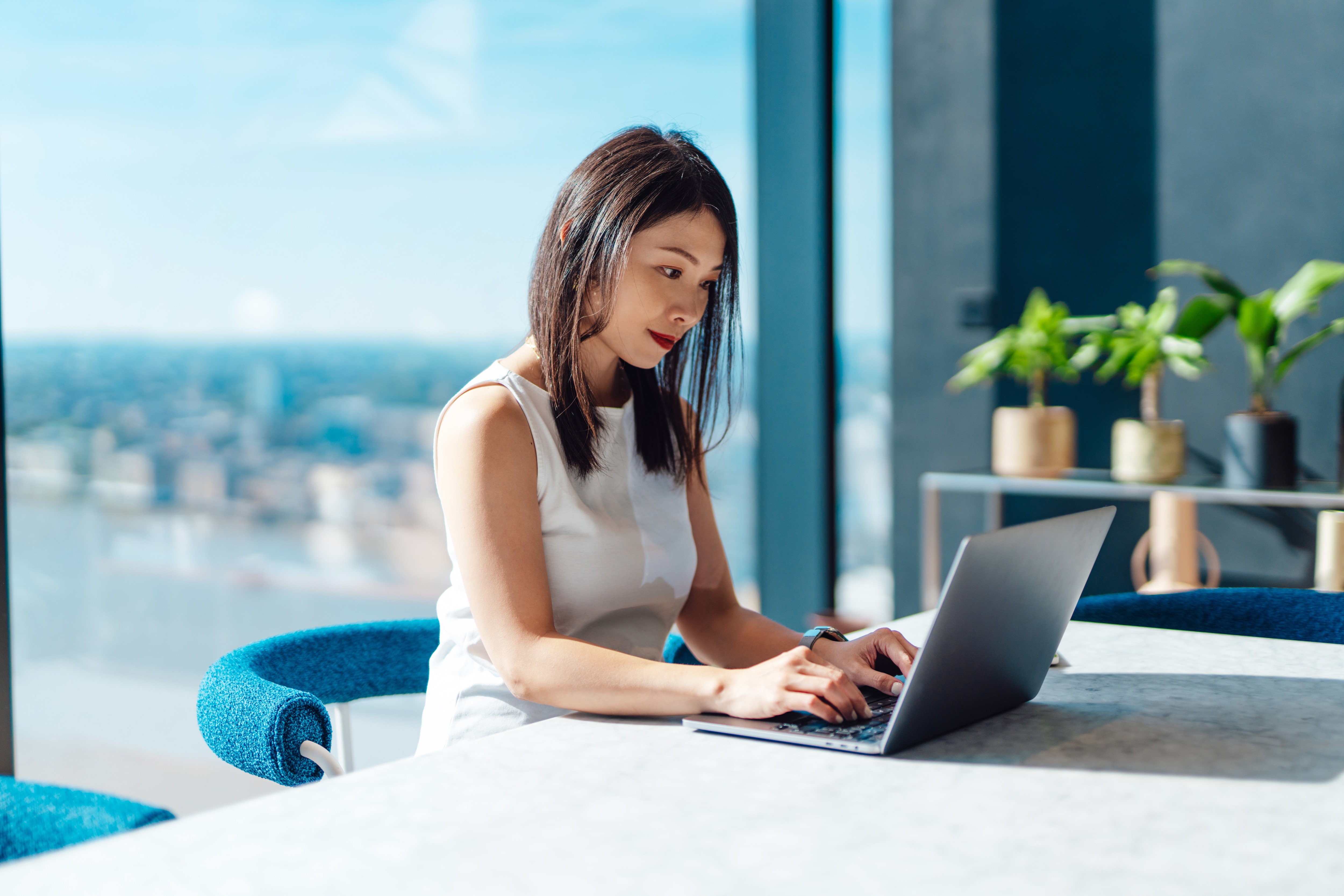 Woman working at computer in an office with window behind her
