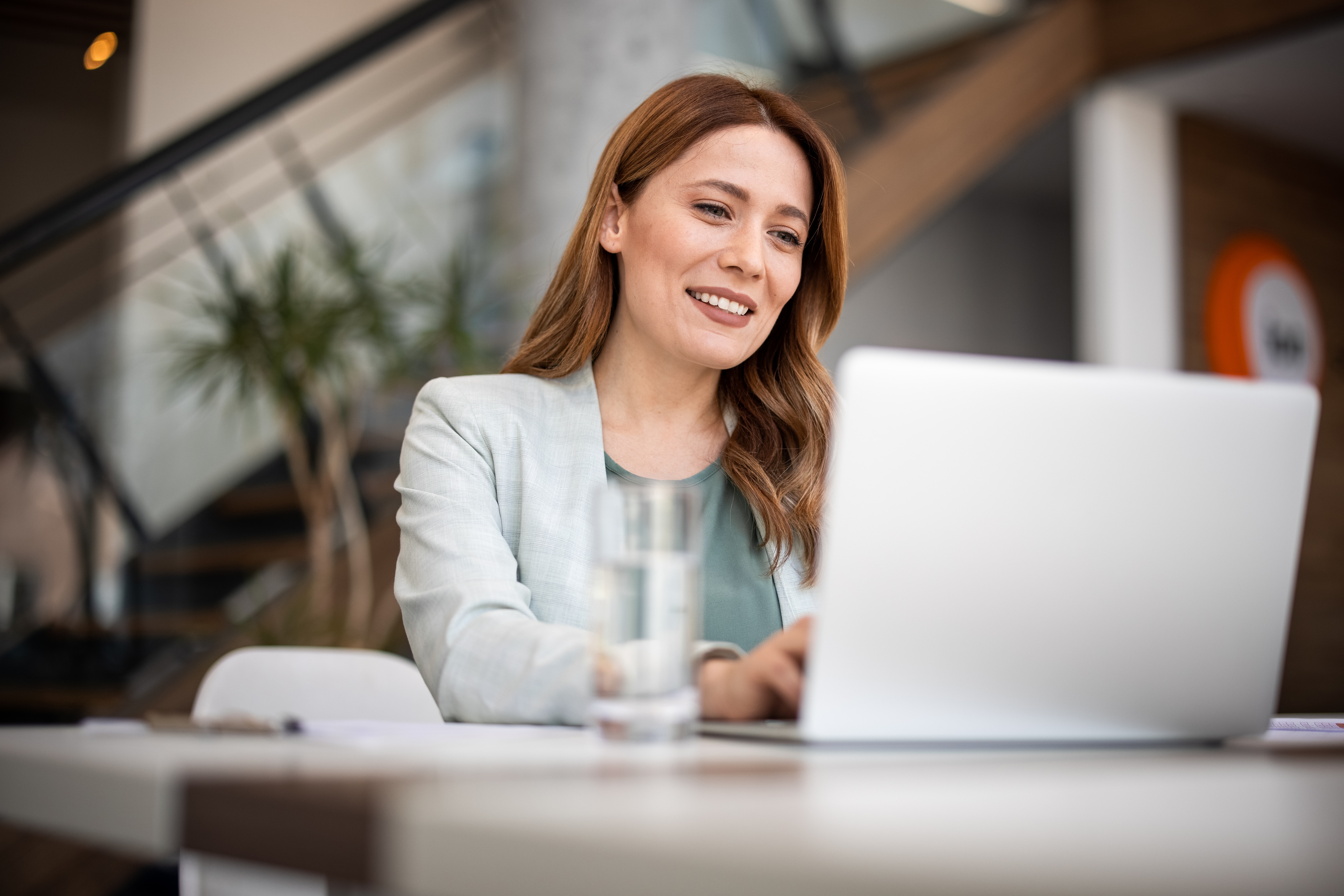 a business woman by the desk using her laptop