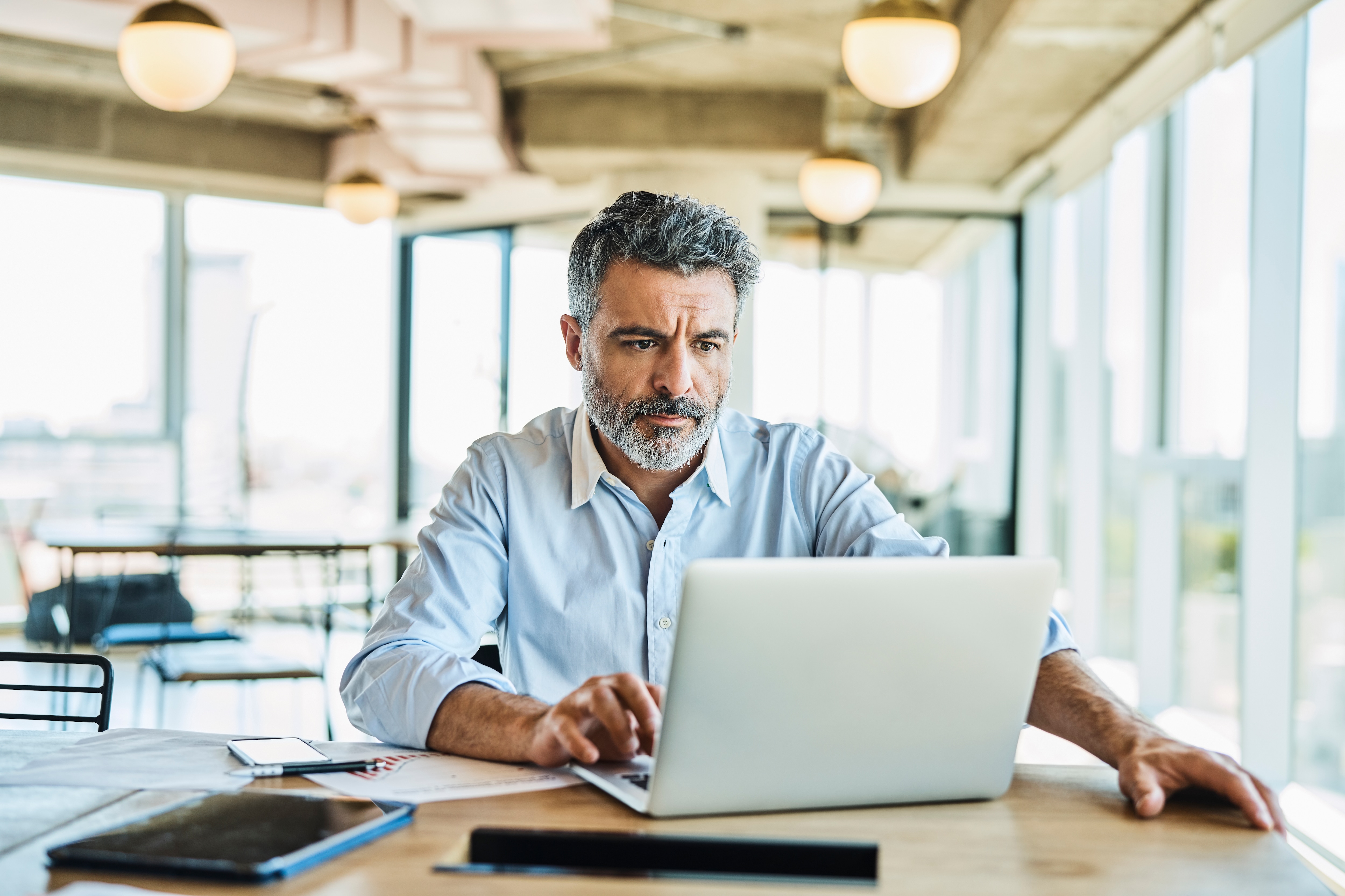 a businessman sitting by the deck looking at his laptop 