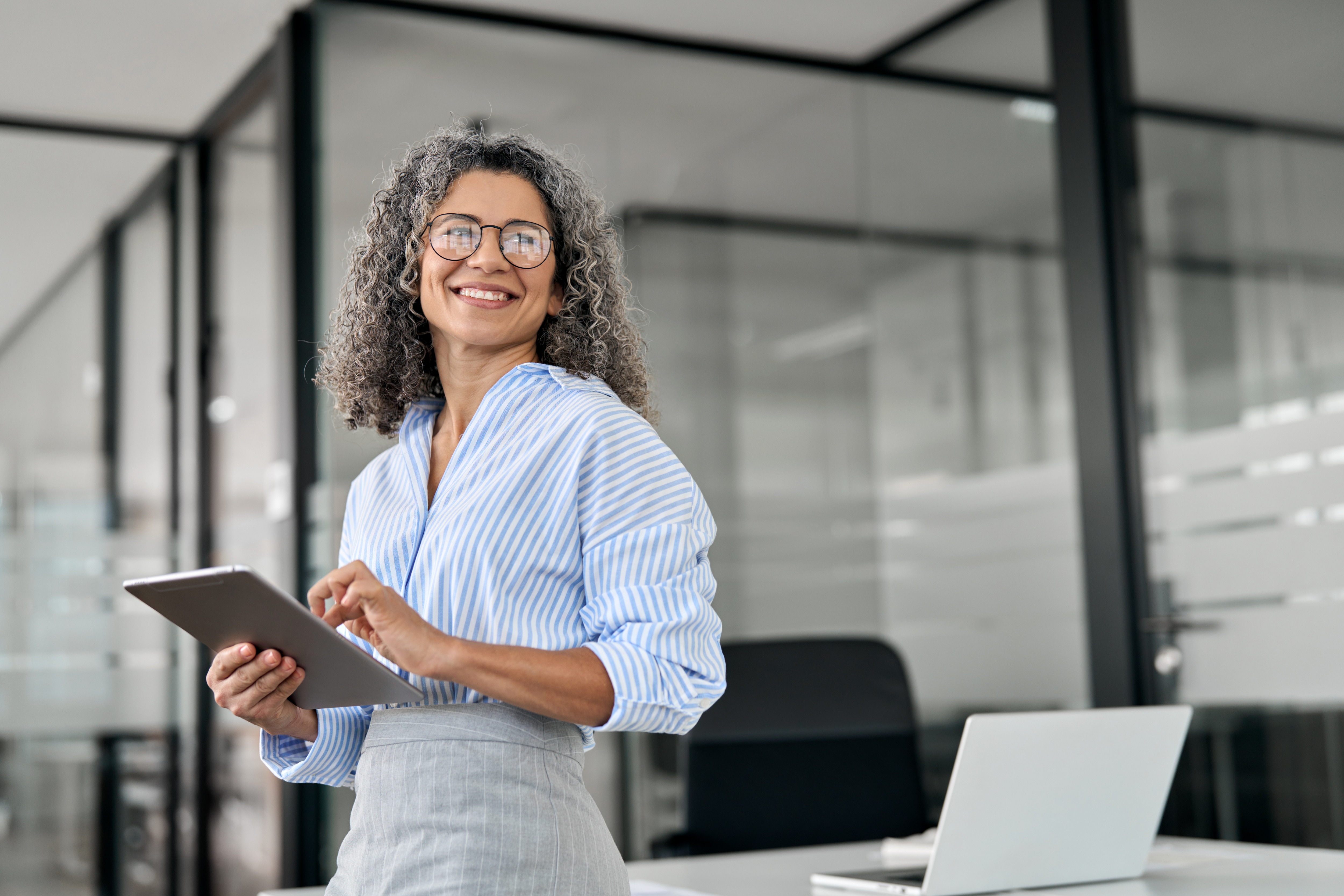 Woman smiling looking to the side with an ipad in her hand