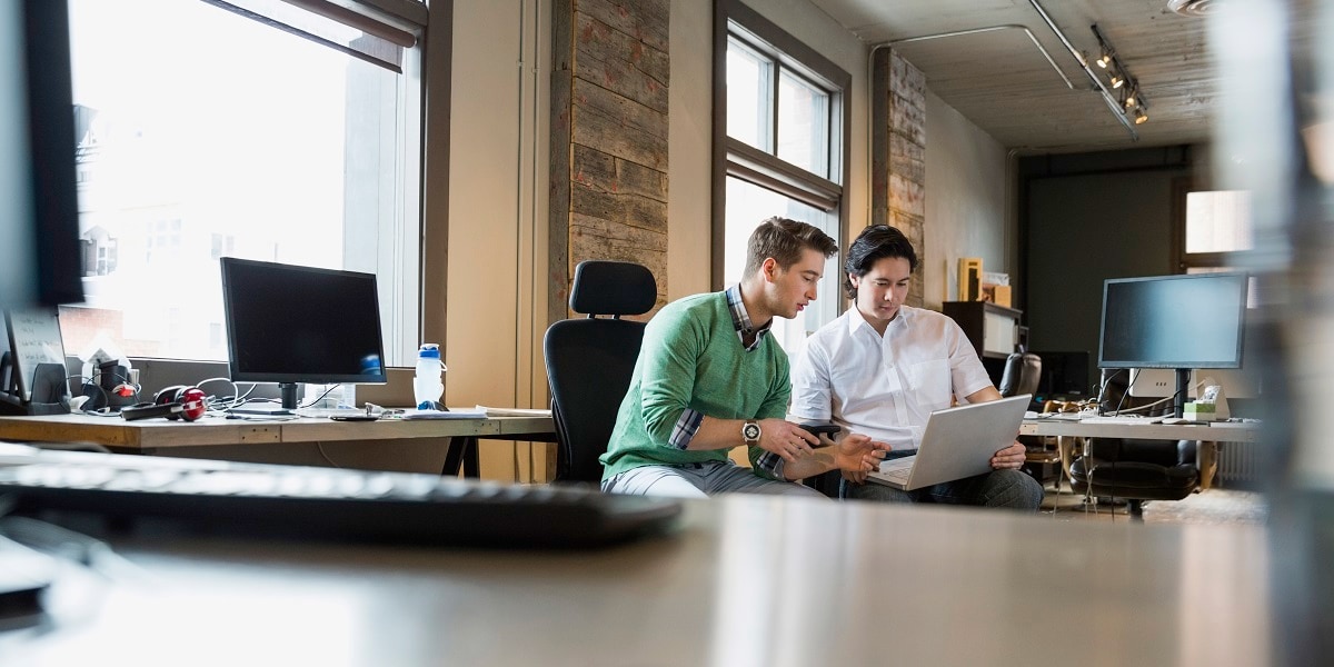 Two business people reviewing information on a tablet in an office setting