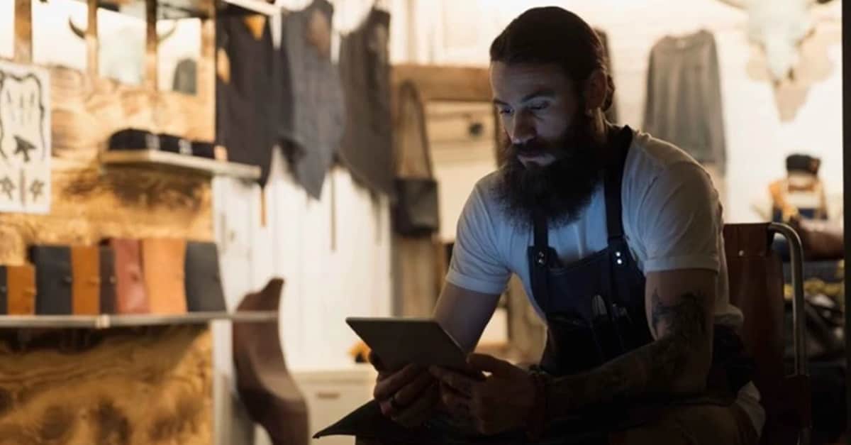 A craftsman sits in his workshop using a tablet