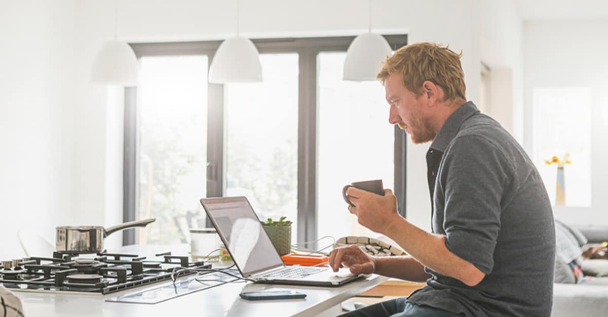 Man uses computer while sitting at kitchen island