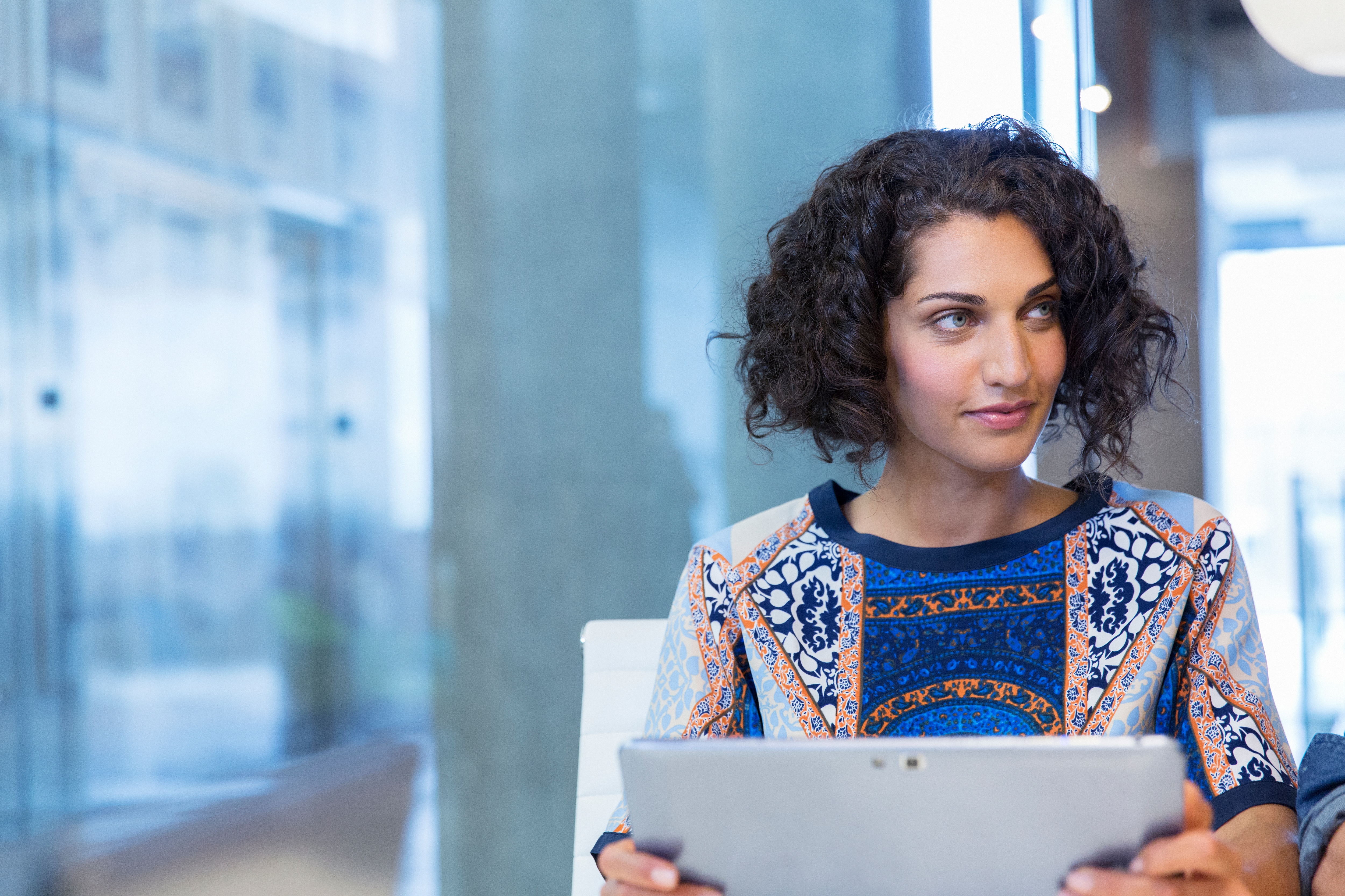 woman holding iPad looking into distance