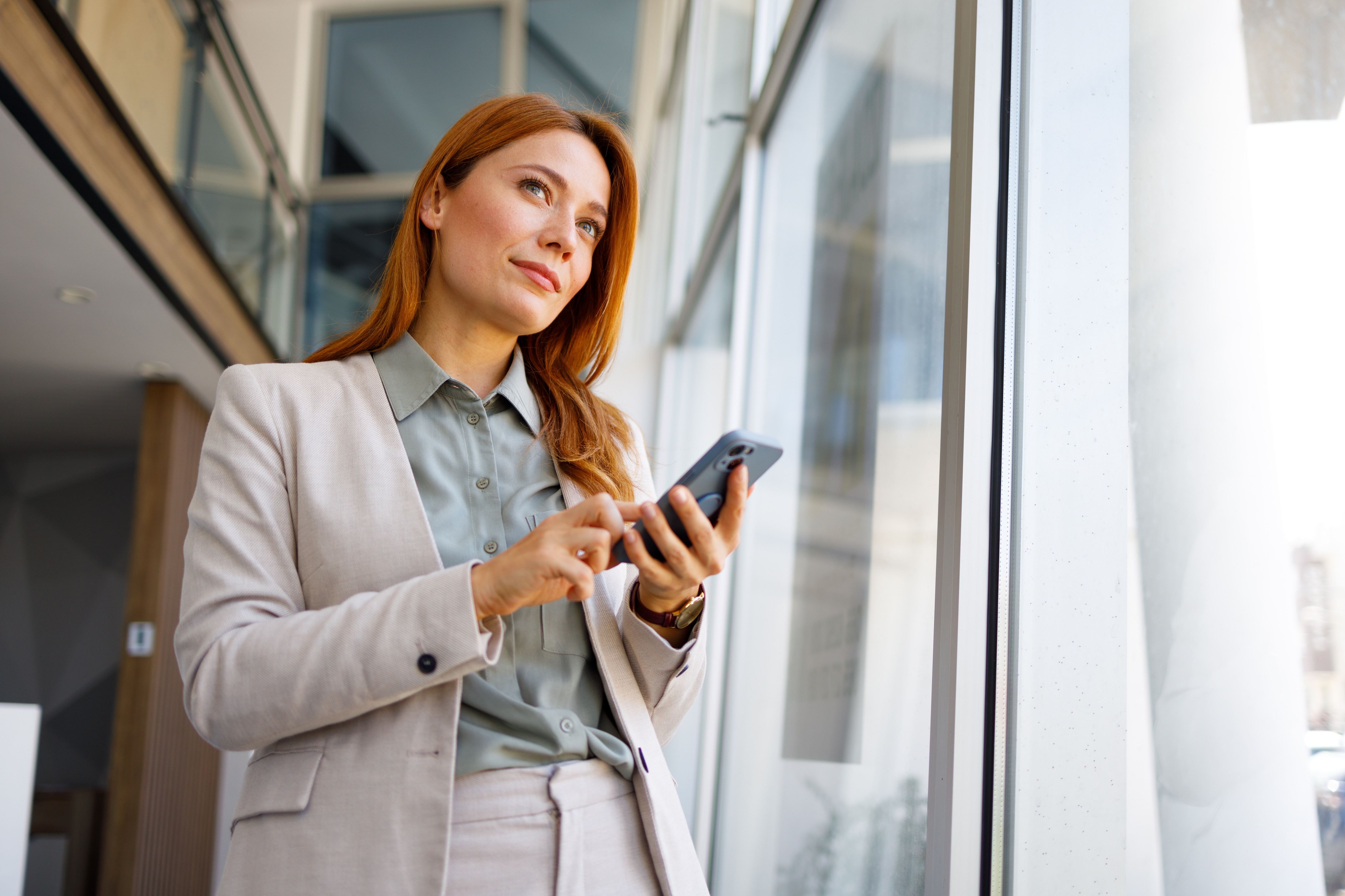 Woman holding phone while walking out of building