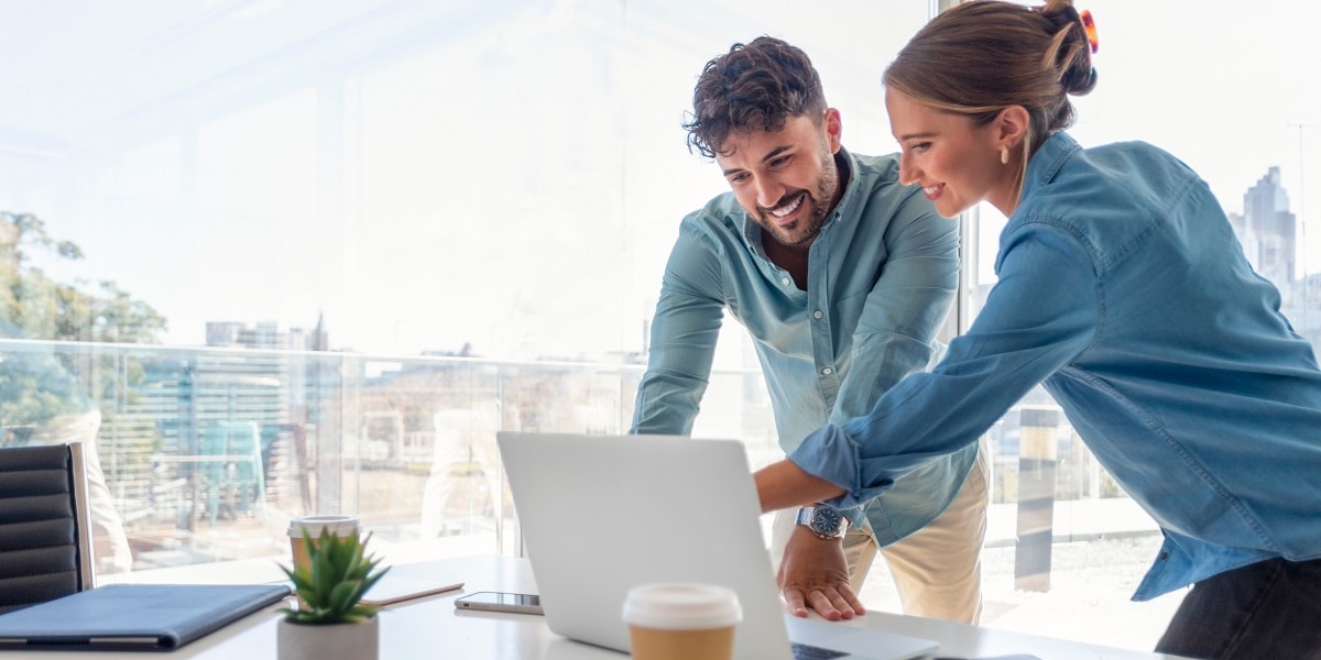 Two office workers looking over a computer.