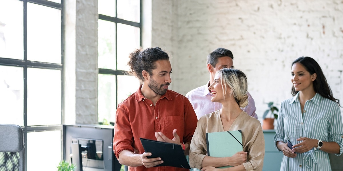 Several co-workers walking and talking while in the office